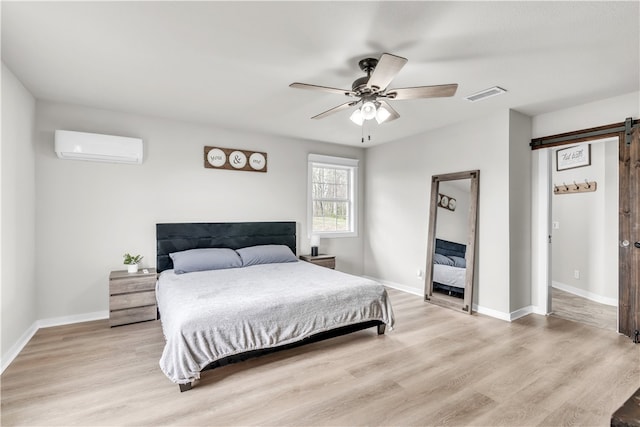 17225 Featherstone Trl, Gentry, AR 72734 - bedroom featuring an AC wall unit, baseboards, a barn door, visible vents, and light wood-style flooring
