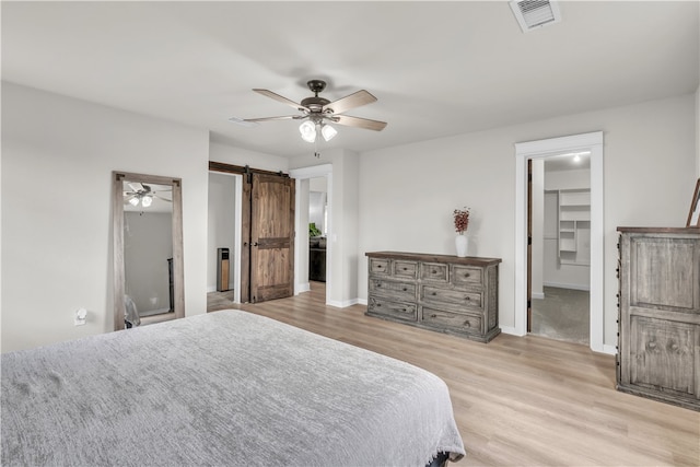 17225 Featherstone Trl, Gentry, AR 72734 - bedroom with visible vents, a barn door, light wood-style flooring, and a walk in closet