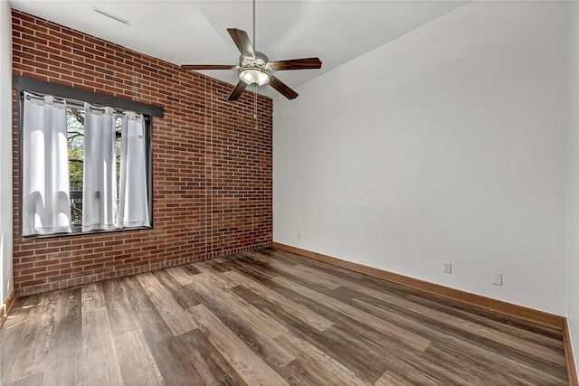 321 E Lafayette St Unit 103, Fayetteville, AR 72701 - empty room with brick wall, a ceiling fan, baseboards, and wood finished floors