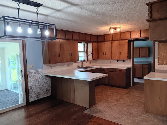 1003 Freeman Ave, Berryville, AR 72616 - kitchen with a sink, a peninsula, light countertops, brown cabinetry, and dark wood-type flooring