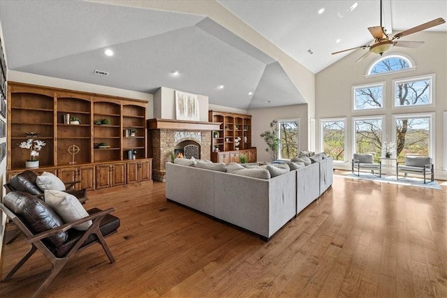 17793 Bluffview Dr, Springdale, AR 72764 - living room with high vaulted ceiling, light wood finished floors, a warm lit fireplace, a ceiling fan, and recessed lighting
