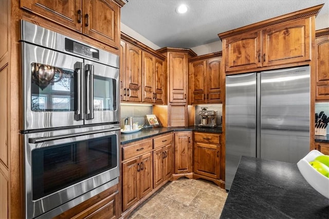 17793 Bluffview Dr, Springdale, AR 72764 - kitchen with appliances with stainless steel finishes, brown cabinetry, recessed lighting, a textured ceiling, and decorative backsplash