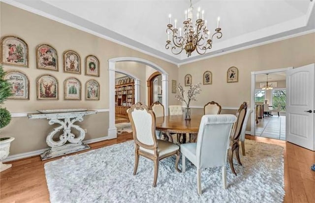 17793 Bluffview Dr, Springdale, AR 72764 - dining space featuring a chandelier, arched walkways, wood finished floors, ornamental molding, and a tray ceiling