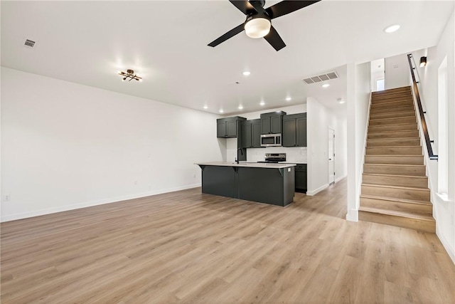 730 N 5th St, Rogers, AR 72756 - unfurnished living room featuring a ceiling fan, light wood-style floors, stairs, and recessed lighting