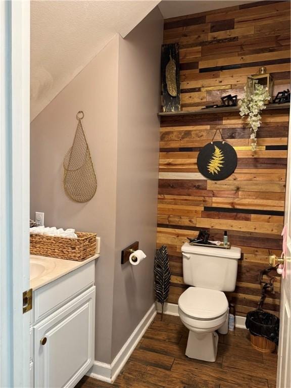 2110 W 8th St, Russellville, AR 72801 - half bath with wooden walls, toilet, baseboards, vanity, and wood finished floors