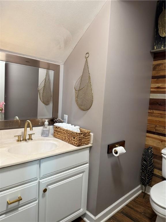 2110 W 8th St, Russellville, AR 72801 - half bath featuring toilet, vanity, wood finished floors, baseboards, and vaulted ceiling