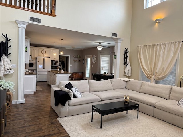 2110 W 8th St, Russellville, AR 72801 - living room featuring ornate columns, ceiling fan, dark wood-style floors, a high ceiling, and healthy amount of natural light