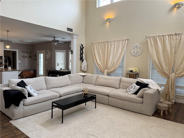 2110 W 8th St, Russellville, AR 72801 - living room featuring wood finished floors, a ceiling fan, ornate columns, and a towering ceiling