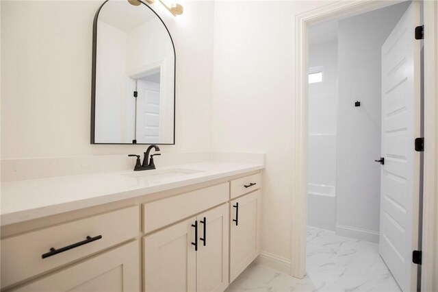 bathroom with vanity, a bathtub, marble finish floor, and baseboards