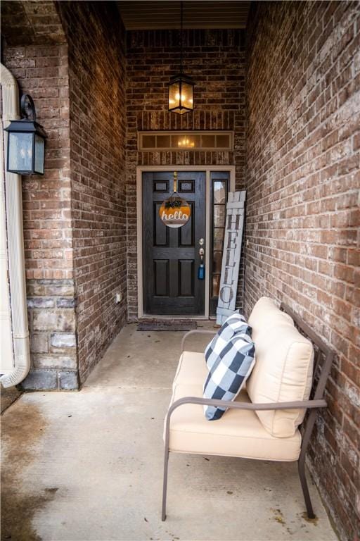 doorway to property with a porch and brick siding