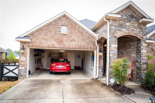view of front of house featuring brick siding, fence, driveway, stone siding, and an attached garage
