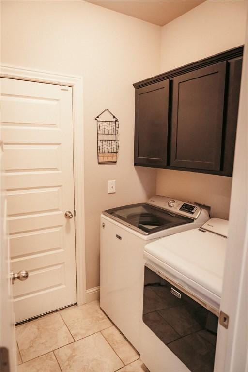 laundry area featuring light tile patterned flooring, separate washer and dryer, and cabinet space