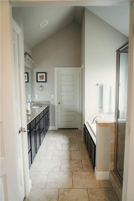 bathroom featuring vaulted ceiling, a bath, vanity, visible vents, and a stall shower