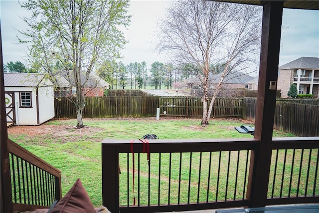 view of yard featuring an outdoor structure, a shed, a wooden deck, and a fenced backyard