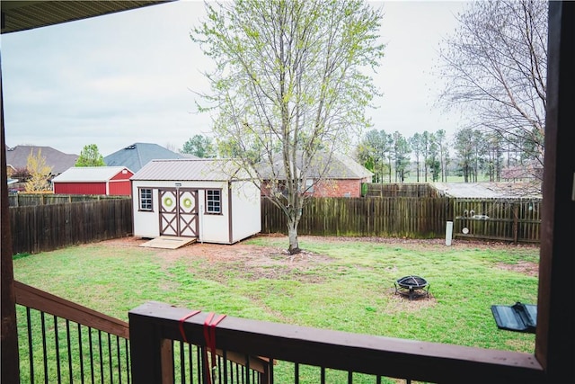 view of yard with a storage unit, an outbuilding, a fenced backyard, and an outdoor fire pit