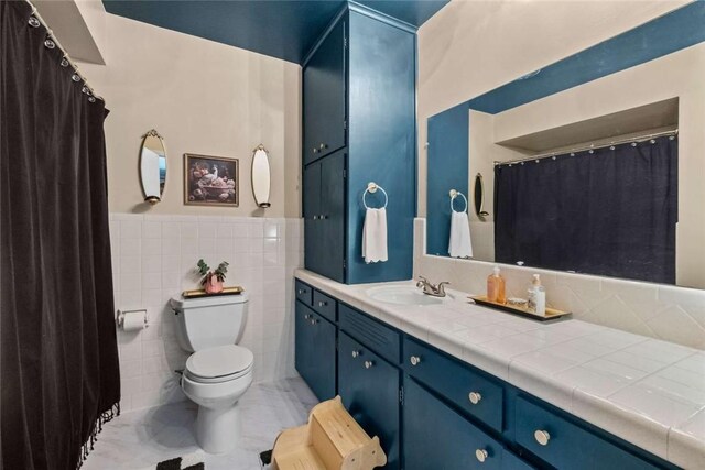 1617 N Applebury Dr, Fayetteville, AR 72701 - bathroom featuring tile walls, toilet, vanity, wainscoting, and marble finish floor