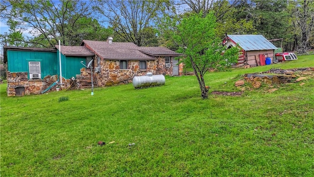 rear view of property featuring stone siding and a yard