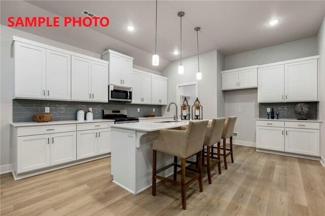 kitchen with a sink, visible vents, white cabinetry, backsplash, and appliances with stainless steel finishes