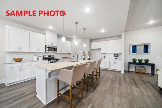 kitchen featuring a sink, decorative backsplash, stainless steel appliances, white cabinets, and dark wood-type flooring