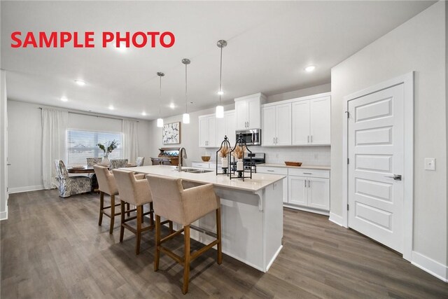 kitchen featuring a sink, a breakfast bar, appliances with stainless steel finishes, dark wood-style floors, and recessed lighting