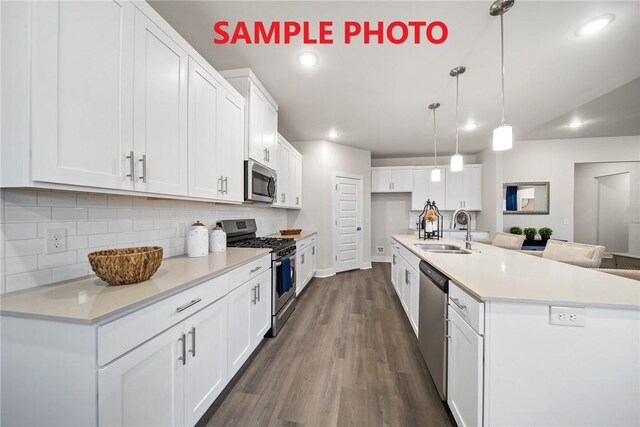 kitchen featuring a sink, white cabinets, backsplash, appliances with stainless steel finishes, and dark wood-type flooring