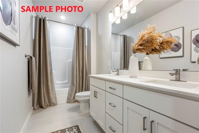 bathroom featuring double vanity, tile patterned floors, toilet, and a sink