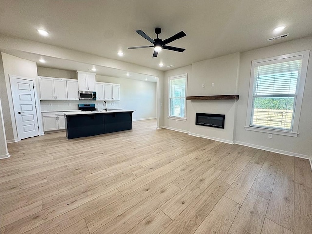 4903 SW Wakanda St, Bentonville, AR 72713 - kitchen with stainless steel microwave, open floor plan, light countertops, white cabinets, and ceiling fan