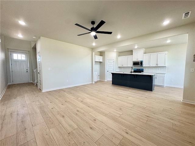 4903 SW Wakanda St, Bentonville, AR 72713 - kitchen featuring stainless steel microwave, white cabinets, light wood-style flooring, ceiling fan, and light countertops