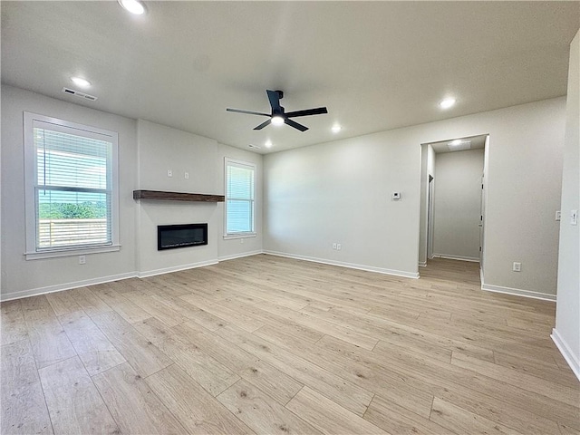 4903 SW Wakanda St, Bentonville, AR 72713 - unfurnished living room featuring a ceiling fan, plenty of natural light, recessed lighting, light wood-style flooring, and a glass covered fireplace