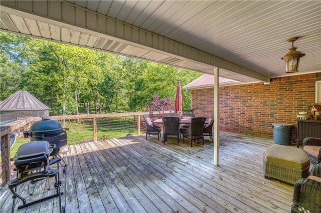 wooden terrace featuring outdoor dining space and area for grilling