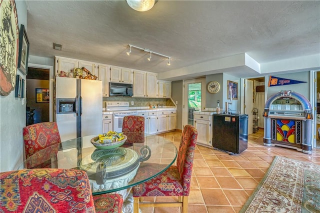 kitchen featuring light tile patterned floors, black microwave, backsplash, refrigerator with ice dispenser, and electric range