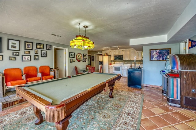 recreation room featuring a textured ceiling, billiards, and tile patterned flooring