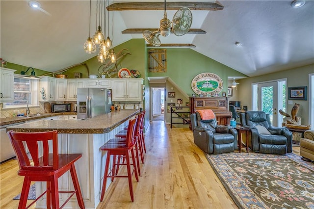 kitchen with an inviting chandelier, open floor plan, light wood-type flooring, a kitchen breakfast bar, and stainless steel appliances