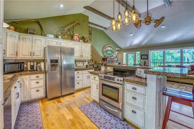 kitchen with a notable chandelier, dark countertops, appliances with stainless steel finishes, light wood-style flooring, and lofted ceiling