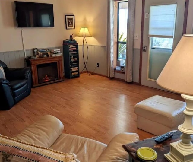 living area with wood finished floors and a wainscoted wall
