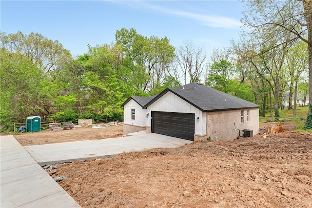 1328 San Miguel Dr, Springdale, AR 72762 - view of property exterior featuring a shingled roof, an attached garage, brick siding, driveway, and view of wooded area
