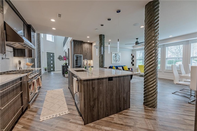 kitchen featuring visible vents, a large island, stainless steel stove, and light wood-type flooring