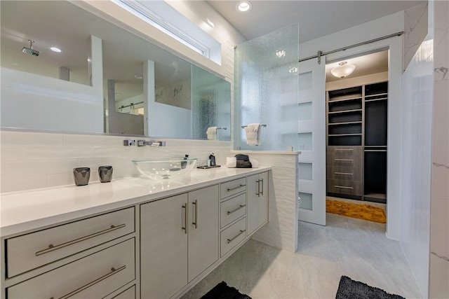 bathroom featuring vanity, a walk in closet, visible vents, decorative backsplash, and a shower