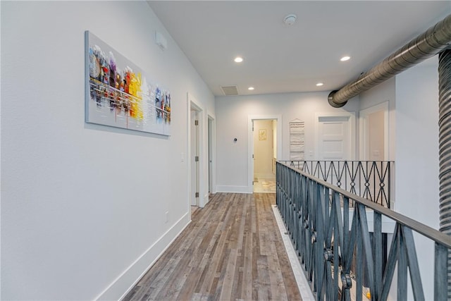 corridor featuring visible vents, baseboards, an upstairs landing, recessed lighting, and wood finished floors