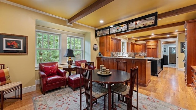 dining room with crown molding, light wood finished floors, beamed ceiling, and baseboards