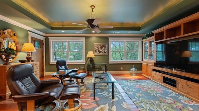 sitting room featuring a raised ceiling, crown molding, baseboards, ceiling fan, and wood finished floors