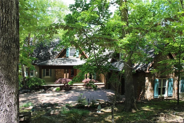 back of property featuring stone siding and covered porch