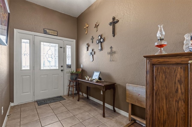 foyer entrance featuring baseboards, light tile patterned flooring, and a textured wall