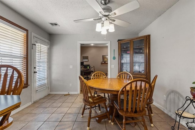 dining room with light tile patterned floors, a textured ceiling, a ceiling fan, visible vents, and baseboards