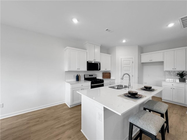 1963 Larkspur St, Springdale, AR 72762 - kitchen featuring stainless steel appliances, a breakfast bar, white cabinets, light wood-type flooring, and recessed lighting