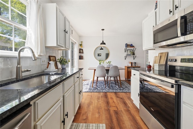 kitchen featuring a sink, backsplash, appliances with stainless steel finishes, and wood finished floors