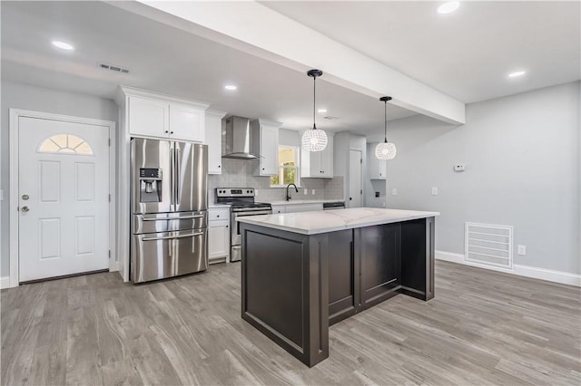 kitchen with white cabinetry, wall chimney range hood, appliances with stainless steel finishes, and visible vents