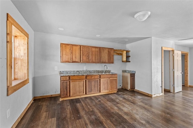 kitchen with brown cabinets, baseboards, a sink, and dark wood finished floors