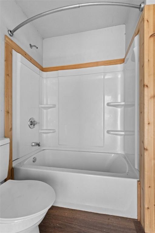 full bathroom with toilet, wood finished floors, and tub / shower combination