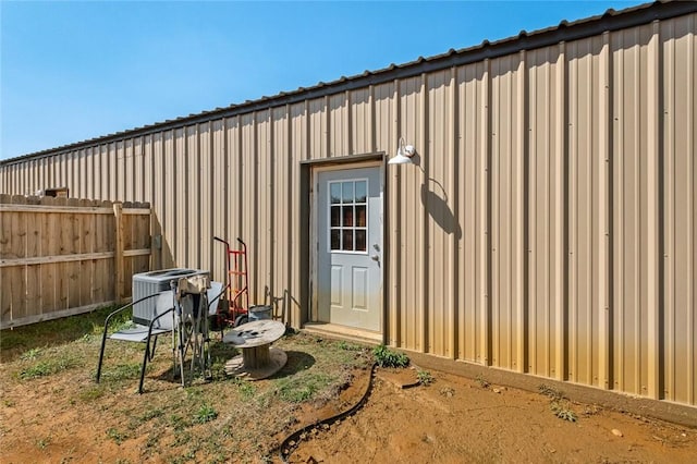 view of outdoor structure with central AC unit and fence